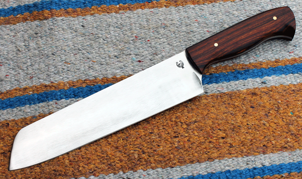großes Chef Messer im Santoku Stil mit einer Klinge aus rostträgem D2 Klingenstahl, angelassen auf 61 Rockwell, damit sehr scharf und schnitthaltig. Die Klinge ist ca. 210 mm lang, 50 mm breit und 3,2 mm stark. Durchgehende Blattangel mit Griffschalen aus schön gemasertem  Wüsteneisenholz. ---Nr. L 013---